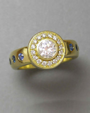 Other Rings 1-9: Round cut diamond surrounded by a bead set frame in 18k yellow gold with flush set blue sapphires down the sides