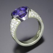 Other Rings 2-1: Oval tanzanite in a partial bezel with pave set diamonds in platinum