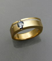 Round cut blue sapphire bezel set in yellow gold with a recessed textured platinum inlay