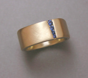14k Yellow gold square shaped band with tapered offset channel of Round Blue Sapphires