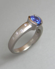 1-10: Round blue sapphire partial bezel set in platinum with small scattered flush set diamonds