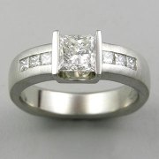 1-11: Princess cut diamond partial bezel set and flanked by channel set smaller princess cut stones on the shank