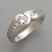 Engagement Ring 2-7: Round cut diamond partial bezel set in white gold with small diamonds channel set down the sides