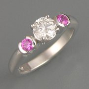 Engagement Ring 2-8: Round cut diamond prong set in white gold with partial bezel set pink sapphires