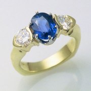 Engagement Ring 3-5: Oval blue sapphire prong set in platinum and 18k yellow gold with partial bezel set diamonds on the sides