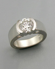 Engagement Ring 3-8: Round cut diamond partial bezel set in platinum with triangular diamonds on the sides
