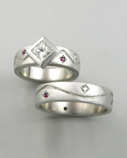 Engagement Ring 4-10: Princess cut diamond full bezel set in white gold with bead set diamonds and rubies shown with matching mens band