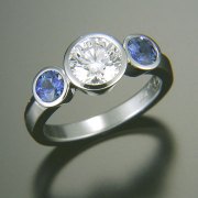 Engagement Ring 4-12: Round cut diamond full bezel set in platinum with full bezel set blue sapphires