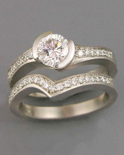 Engagement Ring 4-3: Round cut diamond partial bezel set at an angle in white gold with bead set diamonds shown with matching band