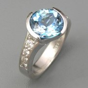 Engagement Ring 5-7: Round cut Aquamarine partial bezel set at an angle in white gold with bead set diamonds on the sides