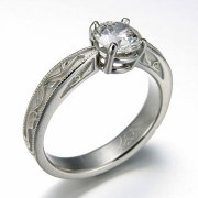 Engagement Ring 6-12: Round cut diamond prong set in platinum with vine detailing on the sides