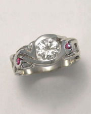 Engagement Ring 6-4: Round cut diamond partial bezel set in white gold with rubies and diamonds on the sides