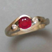 Engagement Ring 6-5: Round cut ruby partial bezel set in yellow gold with diamonds on the sides