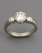 Engagement Ring 6-8: Round cut diamond prong set in white gold with partial bezel set diamonds on sides