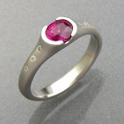 Engagement Ring 7-11: Round cut pink sapphire partial bezel set in white gold with flush set diamonds on the sides