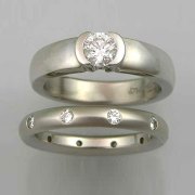 Engagement Ring 7-7: Round cut diamond partial bezel set in white gold shown with flush set diamond band