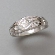 Engagement Ring 8-11: Platinum diamond engagement ring with center round diamond, channel set small diamonds with a calla lily motif