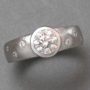 Engagement Ring 8-12: Platinum diamond engagement ring with full bezel set center diamond and flush set scattered small diamonds on sides of band