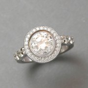 Engagement Ring 9-3: Platinum diamond engagement ring with a halo of small bead set diamonds and larger bead set diamonds on the sides