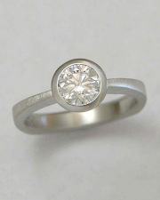 Engagement Ring 9-7: Platinum engagement ring with round center diamond set in a full bezel
