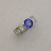 Platinum ring with Sapphire in partial bezel, Flush set side Diamonds